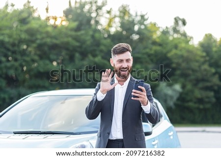 Happy businessman car salesman inspects the car online with a video call, and an application on the phone, a man has fun selling a car