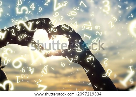 numerology, a young girl folded her hands in the shape of a heart against the background of the sun at sunset, surrounded by numbers Royalty-Free Stock Photo #2097219334