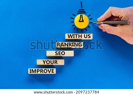 Improve your SEO ranking with us symbol. Wooden blocks with words Improve your SEO ranking with us. Businessman hand. Beautiful blue background, copy space. Business, improve SEO ranking concept. Royalty-Free Stock Photo #2097237784