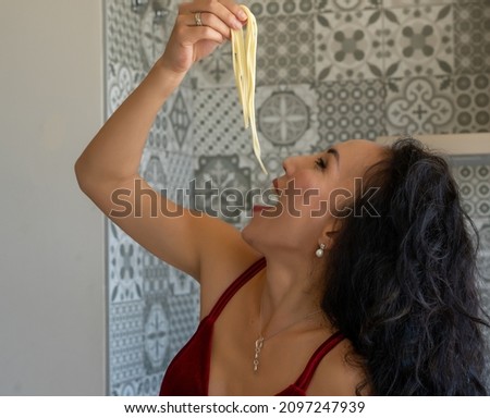 woman putting several pieces of spaghetti in her mouth, head thrown back, close-up horizontal picture
