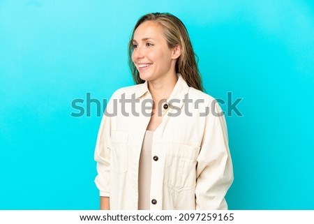 Young caucasian woman isolated on blue background looking side