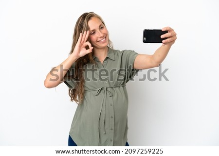 Young caucasian woman isolated on white background pregnant and making a selfie