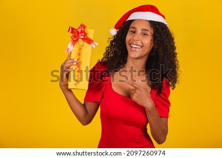 cute afro girl with her christmas present pointing at it 
