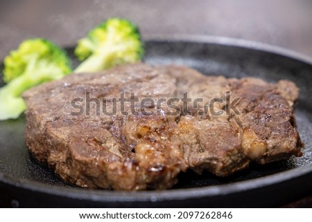 Take a picture of freshly baked hot steaming beef steak on an iron plate