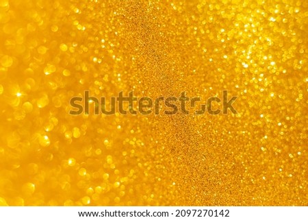 Holiday gold glowing glittering backdrop. Defocused background with glitter. Blurred bokeh.