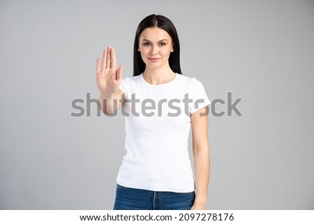 Young woman with bad attitude making stop gesture with her palm outward, saying no, expressing denial or restriction. Negative human emotions, feelings, body language concept 