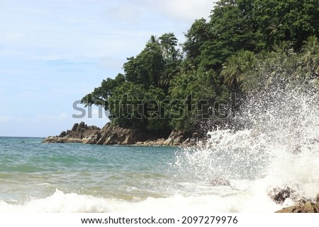ocean waves crashing in the air as they hit large rocks in the beach area.