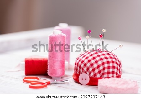 Handmade and sewing background. Spool thread bobbins, pincushion, push pins, needles, scissors, buttons, sewing accessories for needlework on white wooden background. Sewing tools, supplies Royalty-Free Stock Photo #2097297163