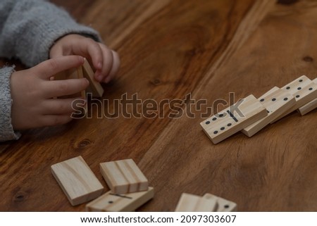 child's hands in gray sweater playing dominoes with blurred focus