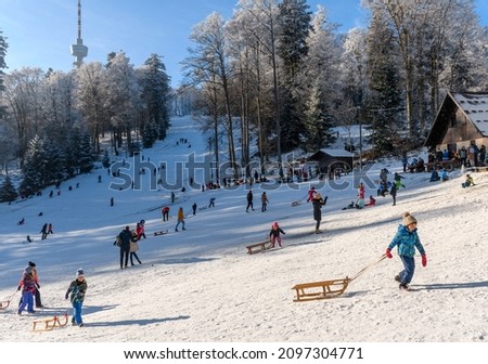 Winter scene with people enjoying in winter activities on sledding hill at Sljeme near Zagreb, Croatia  Families and children having fun on snow