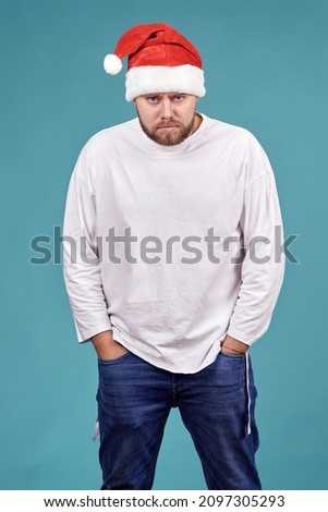 a young man in a Santa Claus hat stands with an angry expression on his face