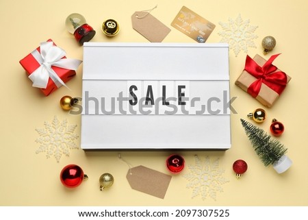 Lightbox with word Sale, gift boxes, credit card and Christmas decorations on beige background, flat lay