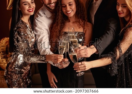 Happy friends with glasses of sparkling wine celebrating New Year indoors