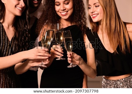 Happy friends with glasses of sparkling wine celebrating New Year indoors, closeup