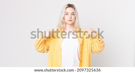 pretty albino woman looking proud, positive and casual pointing to chest with both hands