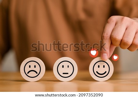 customer services best excellent business rating experience, Positive Review and Feedback, Satisfaction survey concept. Hand of a businessman chooses a smile face on wood block. Royalty-Free Stock Photo #2097352090