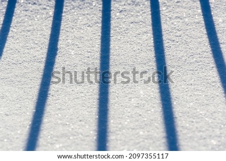 Snow. There are shadows from the fence in the snow.