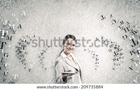 Young woman holding tablet pc in hands and letters flying around