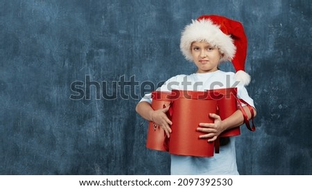 a child with red Christmas boxes poses for the camera