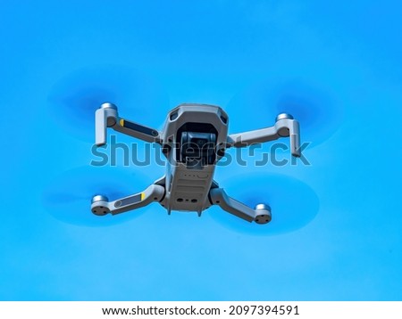 The flight of the drone against the blue sky. Drone in the air. Filming from the air. Take pictures in flight. Mini helicopter. Propeller blades. Ascend to the skies. Air space. Electronic technology.