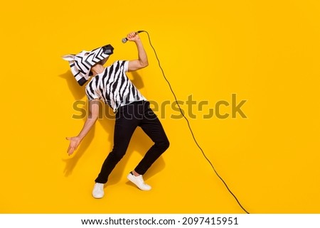 Full length photo of freak famous singer in zebra mask sing mic sound isolated over bright yellow color background Royalty-Free Stock Photo #2097415951