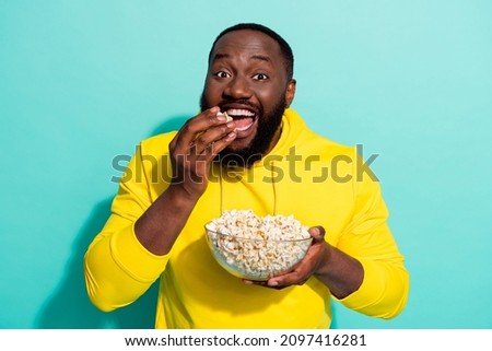 Photo of excited positive guy film addicted eat pop corn wear sweater isolated over cyan color background