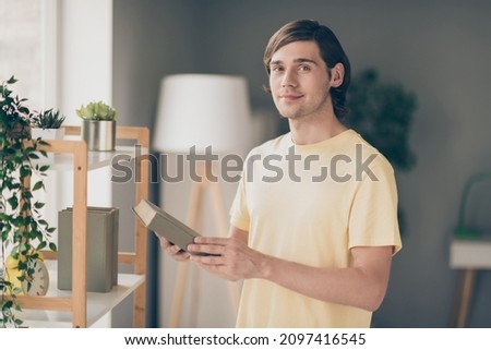 Photo of cheerful positive clever guy hands hold favorite novel book library wear yellow t-shirt home indoors