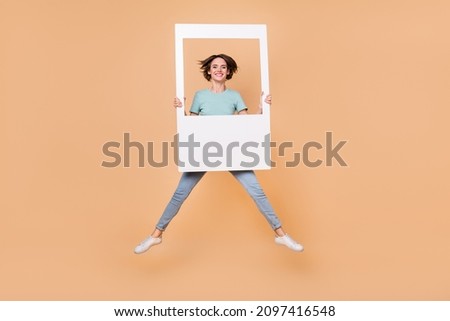 Full size photo of young cheerful woman make picture album jump up isolated over beige color background