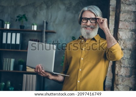 Photo of handsome mature guy dressed yellow shirt arm spectacles writing modern gadget indoors workshop workstation