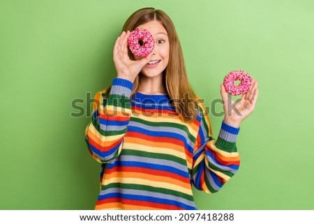 Portrait of attractive trendy funny girly cheerful girl holding two pink donuts closing eye isolated over bright green color background