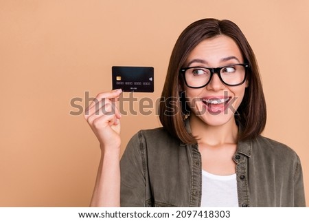 Photo of curious funny lady presenting plastic debit card wear specs khaki shirt isolated beige color background