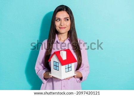 Photo of dreamy real estate agent lady look empty space hold house figure wear purple shirt isolated teal color background