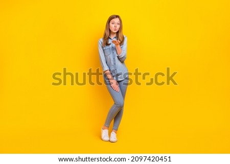 Full length photo of flirty small blond girl blow kiss wear jeans shirt footwear isolated on yellow color background