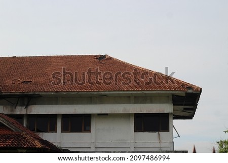 Picture of the roof of a house that has not been used for a long time and is starting to look damaged, the photo is taken from the front