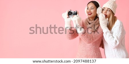 Beautiful sisters with photo camera taking picture on pink background with space for text