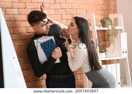 Beautiful young secretary seducing her boss in office. Concept of harassment Royalty-Free Stock Photo #2097493897