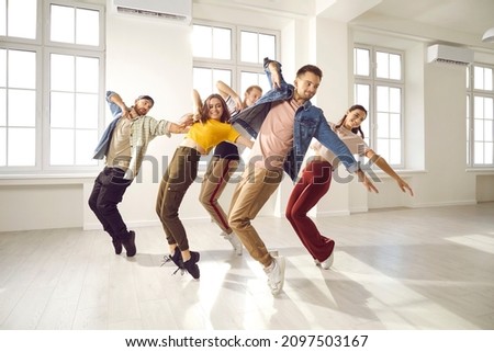 Happy young professional hip hop dancers practice moves in studio together. Smiling active millennial group dance prepare for concert. Youngsters moving to music. Subculture and hobby concept.