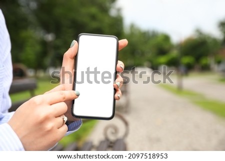 Young woman pointing on blank mobile phone screen outdoors, closeup