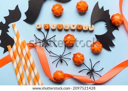 Word HALLOWEEN with candies and decor on blue background