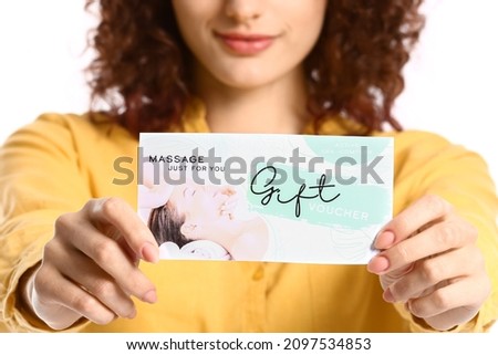 Pretty young woman with gift voucher on white background