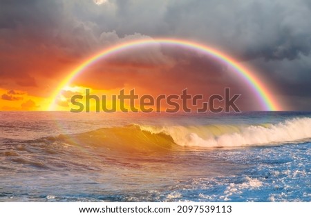 Amazing sunset over the stormy sea with rainbow