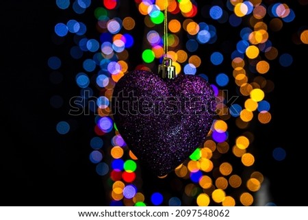 A closeup of a heart-shaped Christmas toy against bokeh lights background