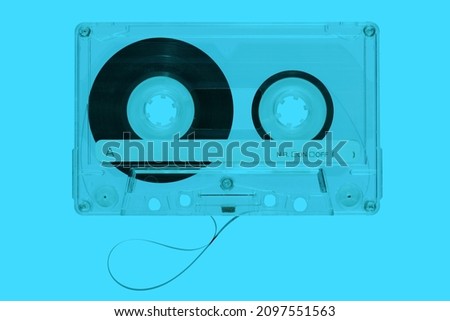 Top view of plastic vintage audio cassette with magnetic tape on bright blue background