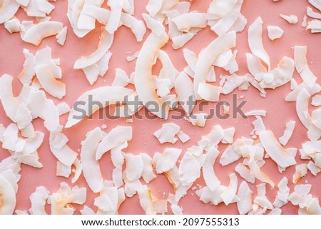 Dried coconut chips on pink background.