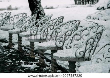 Park bench chairs covered in snow. Winter snow season in Bulgaria. Beautiful metal chair row. High quality photo