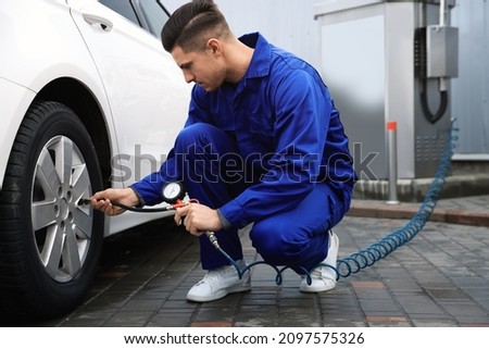 Professional mechanic inflating tire at car service Royalty-Free Stock Photo #2097575326
