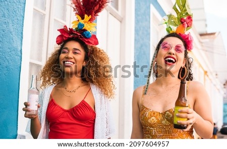 Carnaval in Brasil, people in costume at street party. Brazilian holiday, two women walk and smile together.