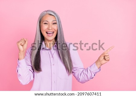 Portrait of attractive lucky cheerful gray-haired woman showing copy space luck isolated over pink pastel color background