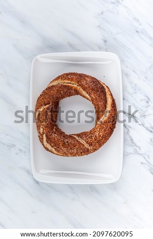 Simit or gevrek. Turkish bagel with sesame. Traditional Turkish bakery and street food. Fresh Turkish bagel on a marble background. 