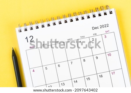 Close-up December 2022 desk calendar on yellow background.